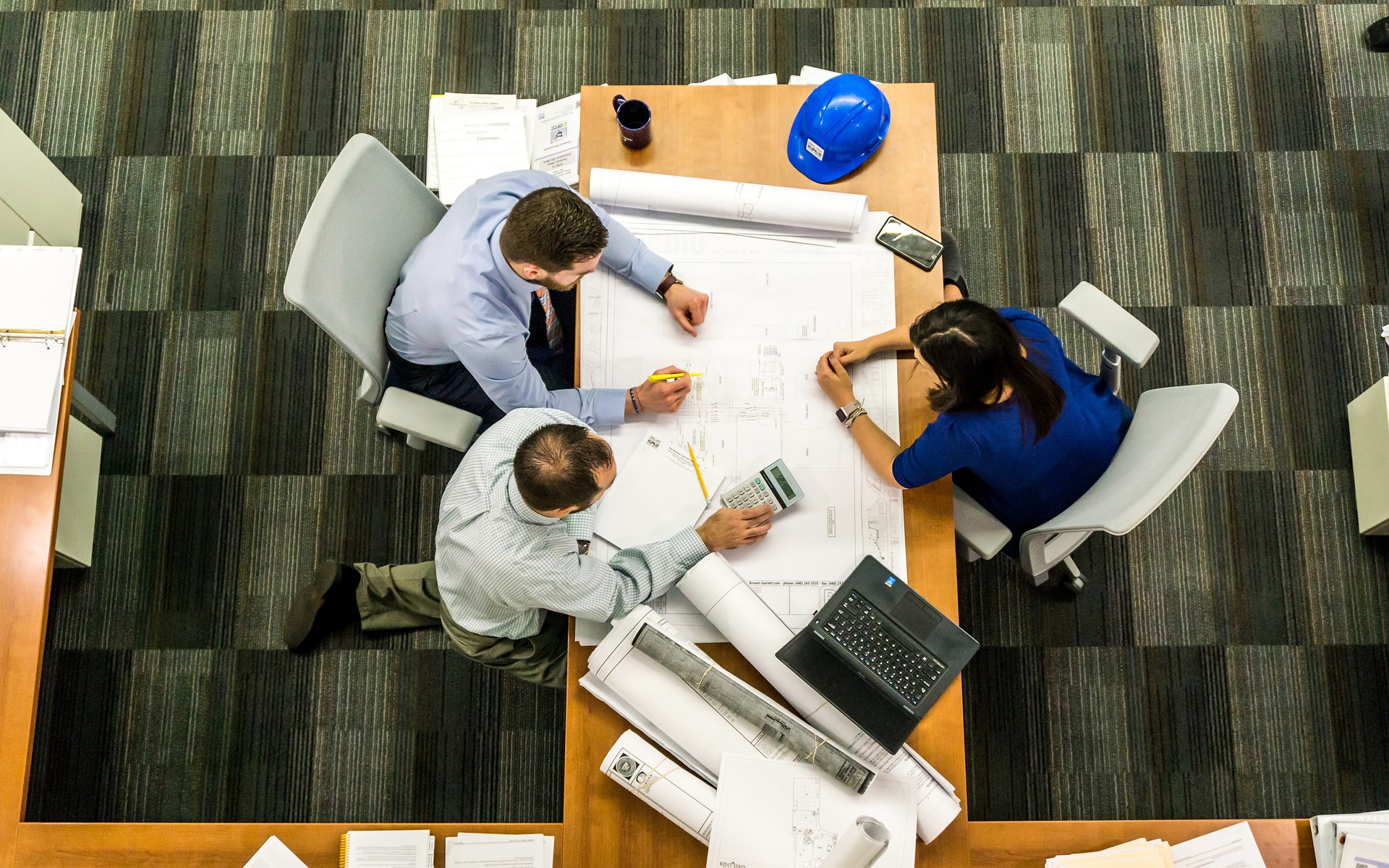 Group of workers discussing measurements and details of a blueprint
